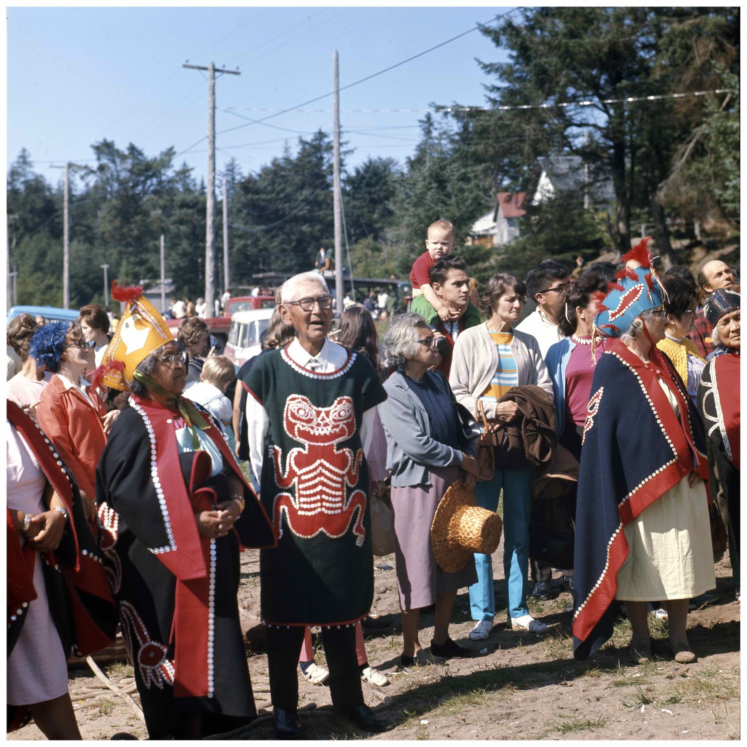 Image taken at a pole raising ceremony in Masset. The pole was carved by Robert Davidson, Jr. This image shows a section of the crowd gathered for the ceremony, many of whom are in what appears to be ceremonial dress.