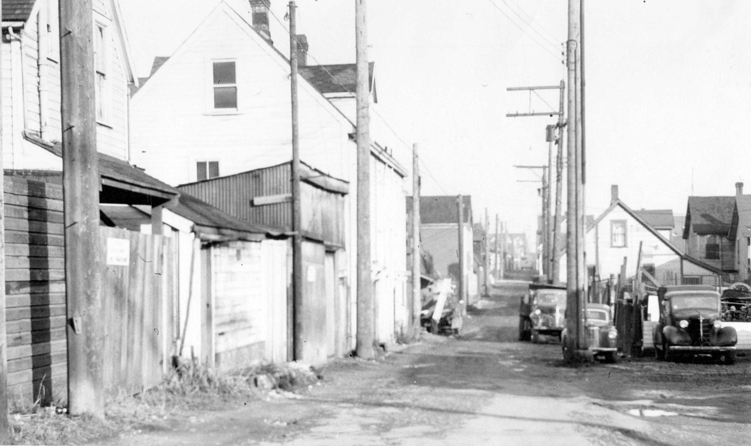 1958 View of Hogan's Alley, cars and trucks parked in alley.