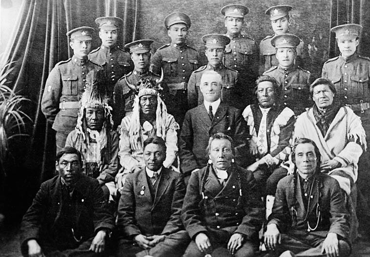 Black and white photo of Indigenous WWI soldiers pictured with Indigenous chiefs in traditional clothing and a white man named W.M. Graham.