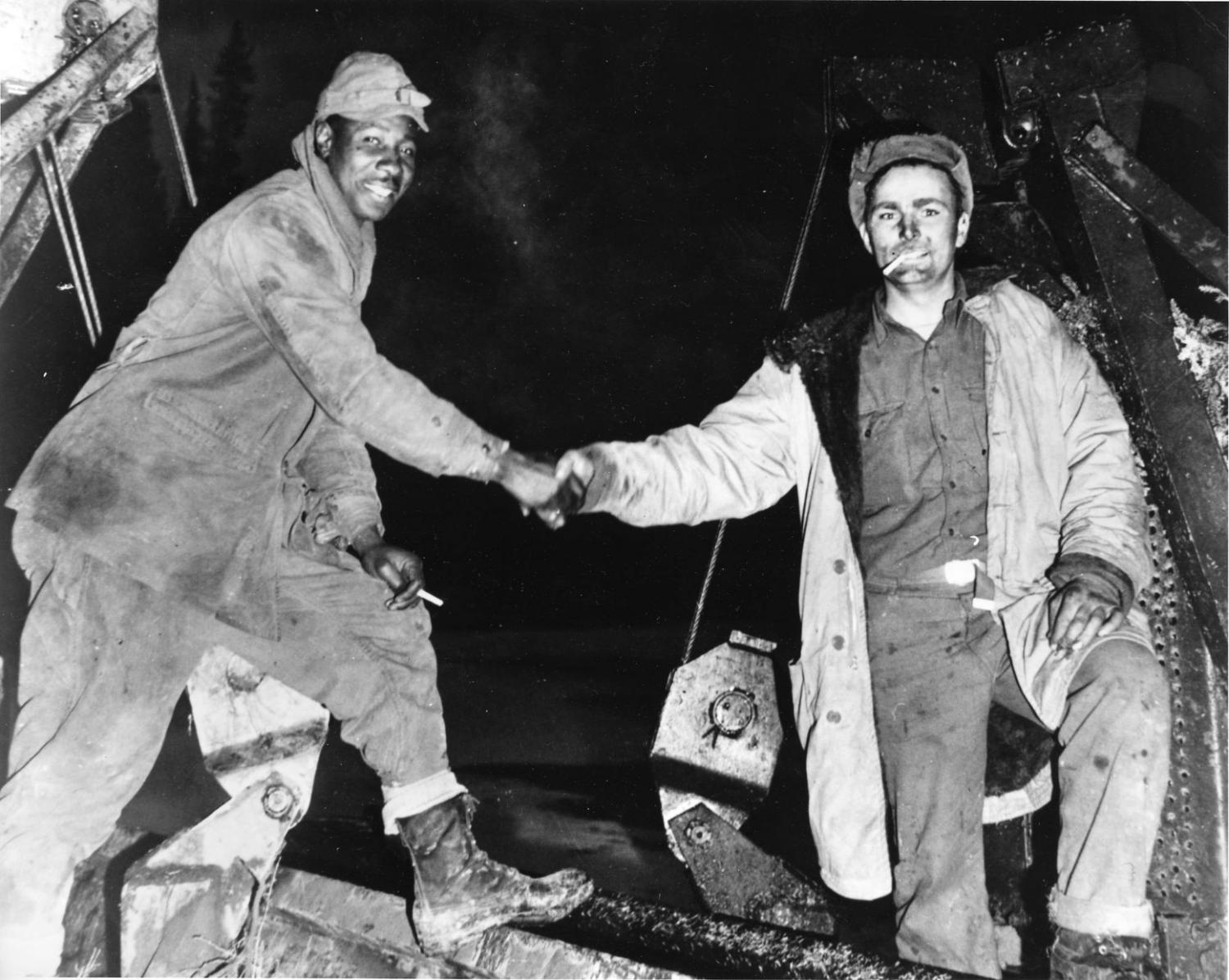 Meeting of bulldozers at Beaver Creek, Yukon Territory, 25 October 1942. Left: Corporal Refines Sims, Jr. (Philadelphia), 97th Engineers. Right: Pvt. Alfred Jalufka (Kennedy, Tex), 18th Engineers.