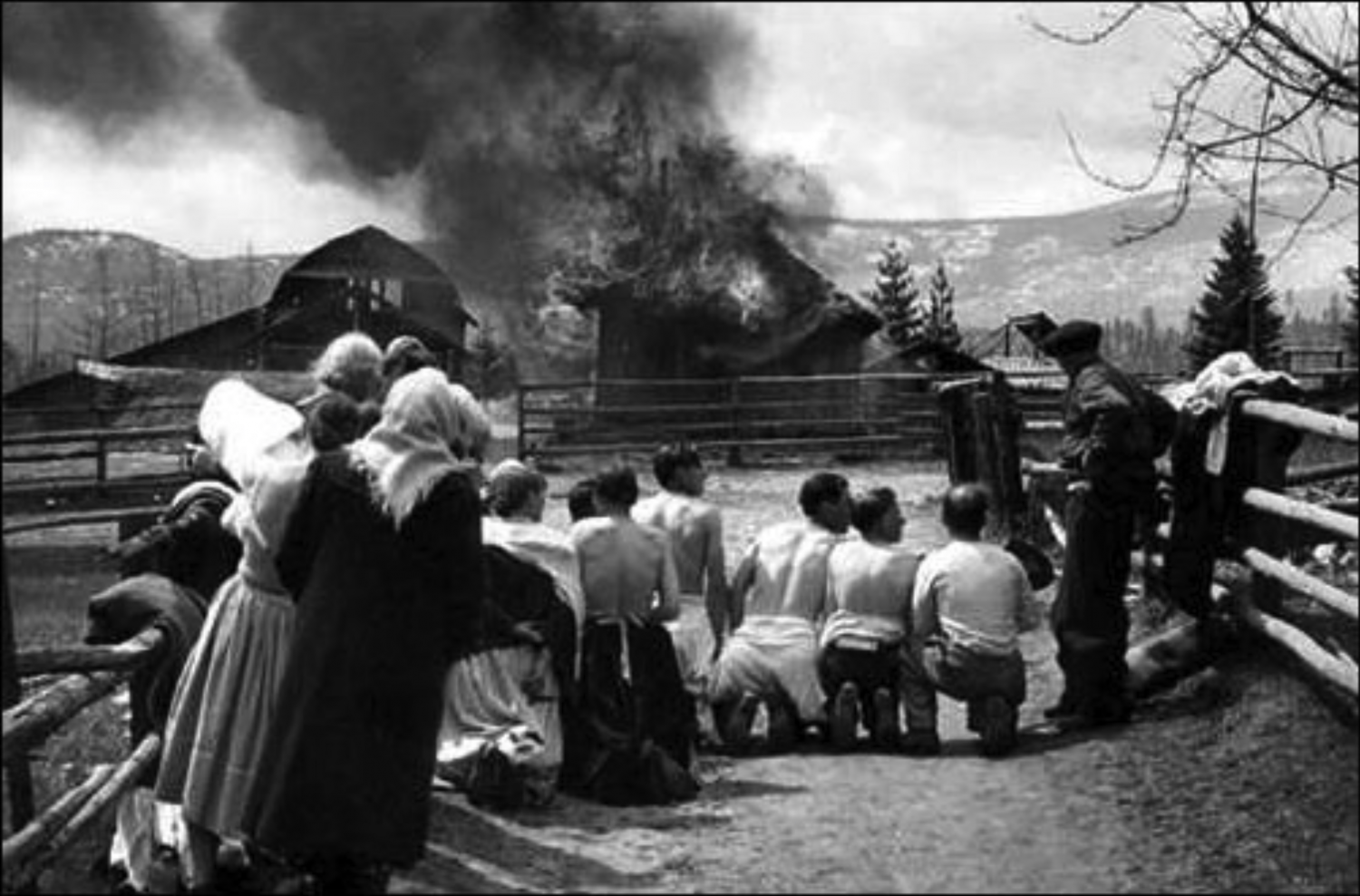 Doukhobor men and women kneel on road facing a burning house, Krestova, B.C., ca. 1950