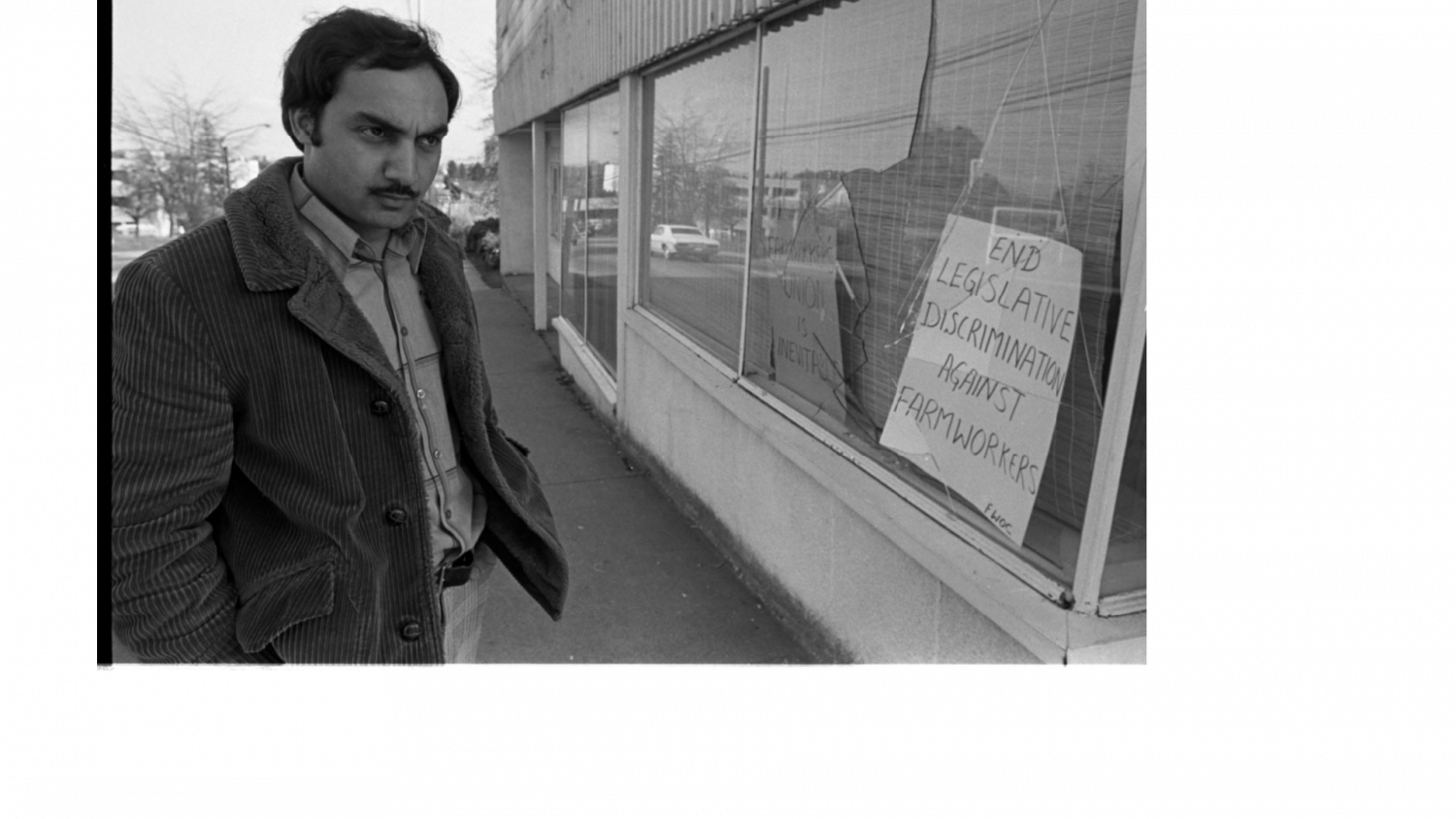 Farm Workers Organizing Committee President Raj Chouhan stands in front of a vandalized FWOC office window.