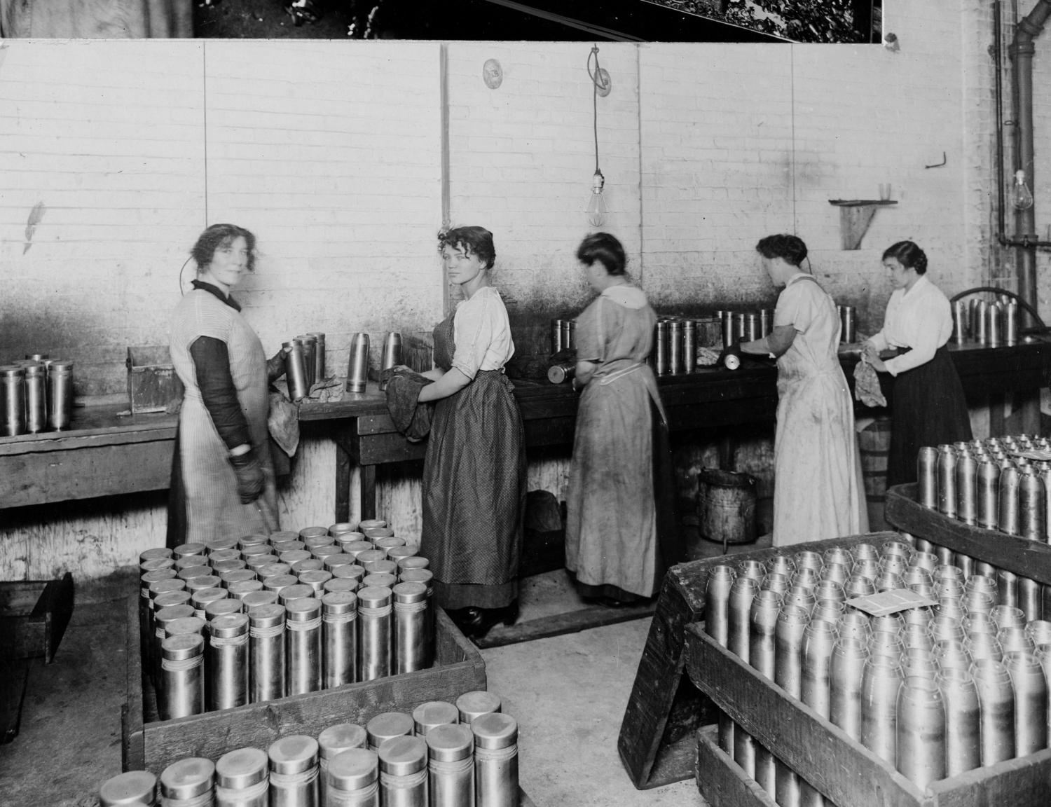 Women packing munitions in a factory with their backs turned.