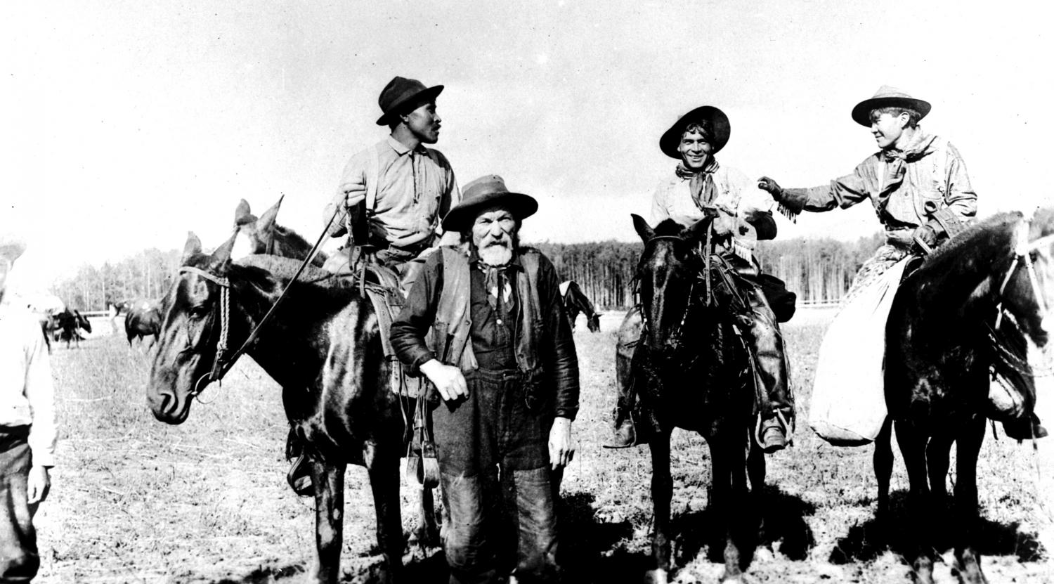 Legendary packer Jean Caux stands by a few horses and young Indigenous packers.