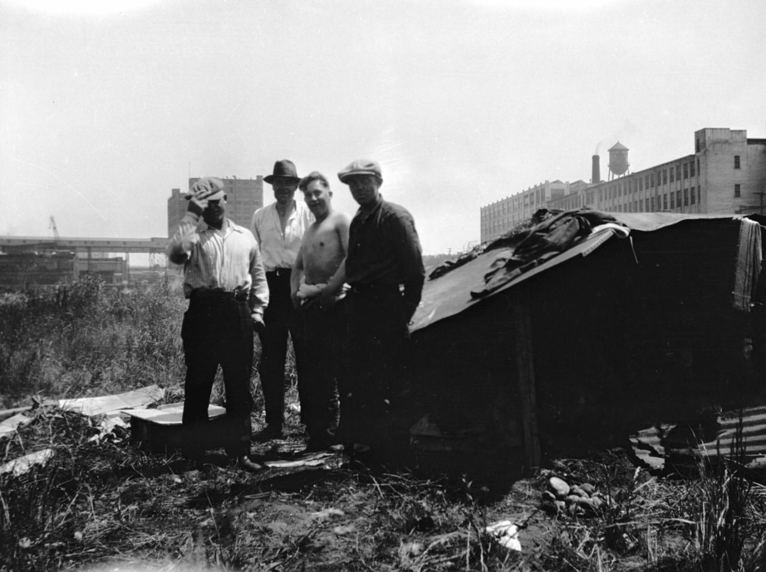 Men standing by a makeshift shelter in the 'Jungle' on the site of the old Hastings Sawmill.